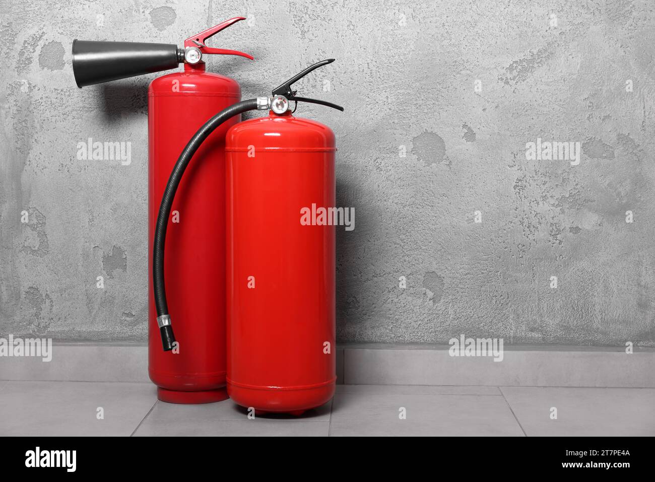 Red fire extinguishers near grey wall, space for text Stock Photo Alamy