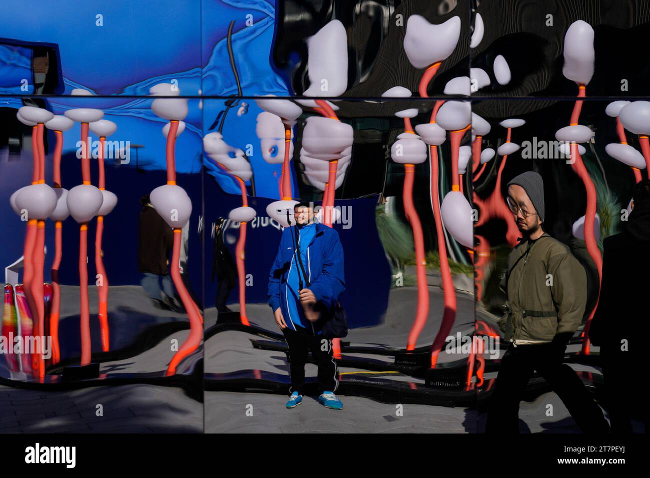 A man is reflected on a distortion panels as he takes a selfie with a ...