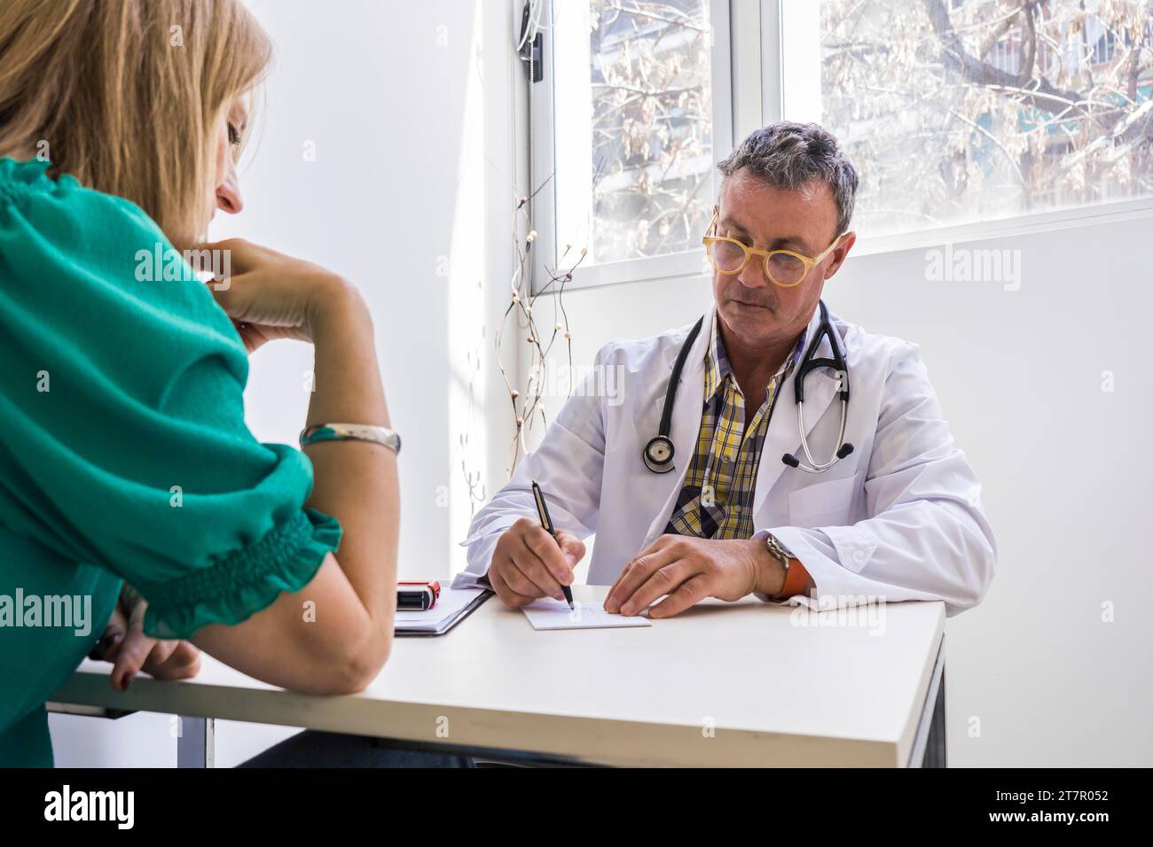 Low angle view of male doctor writing prescription to his patient at his medical office Stock Photo