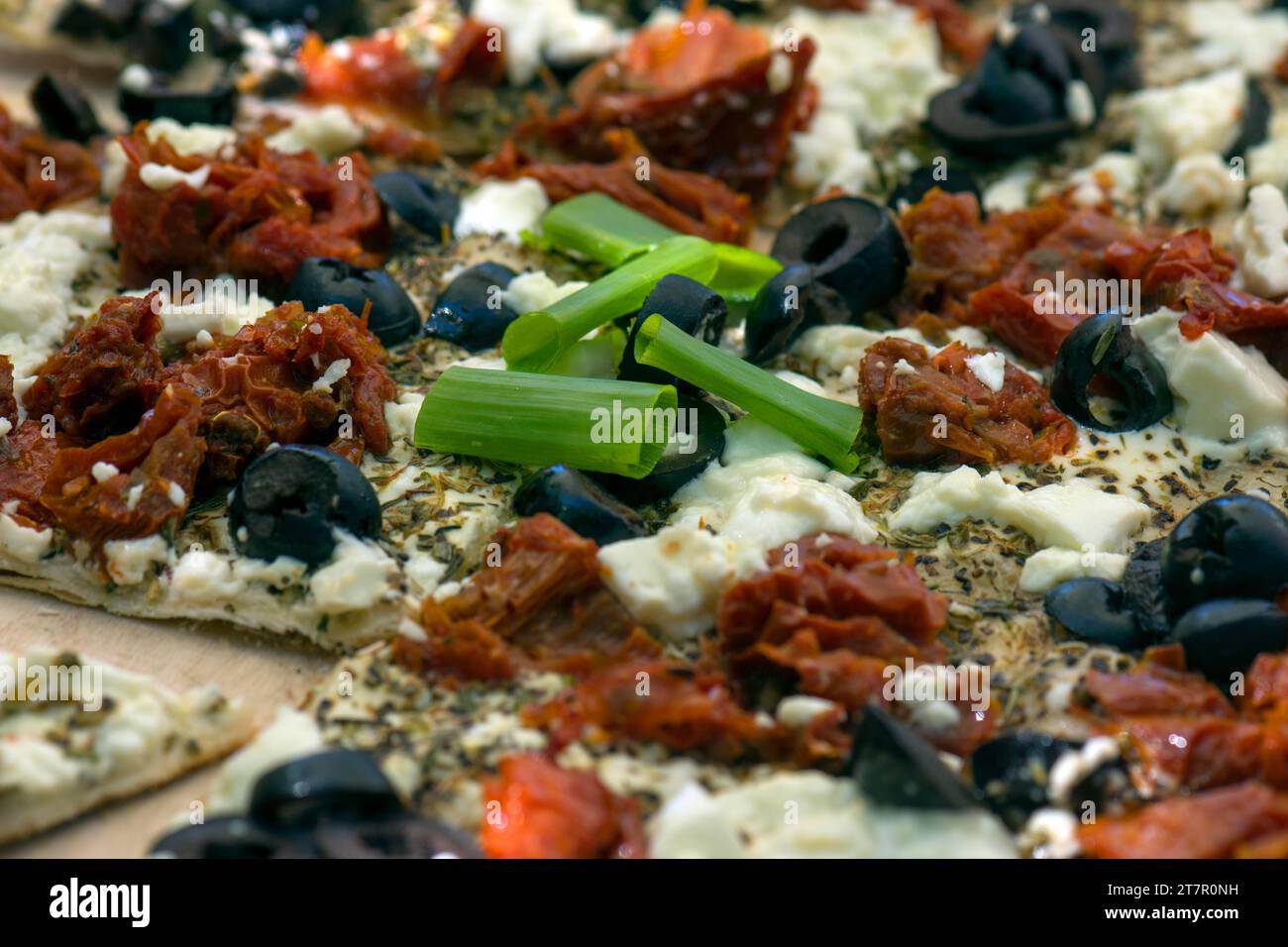 Tarte flambee with sun-dried tomatoes, feta cheese, olives and chives, close up, Bavaria, Germany Stock Photo