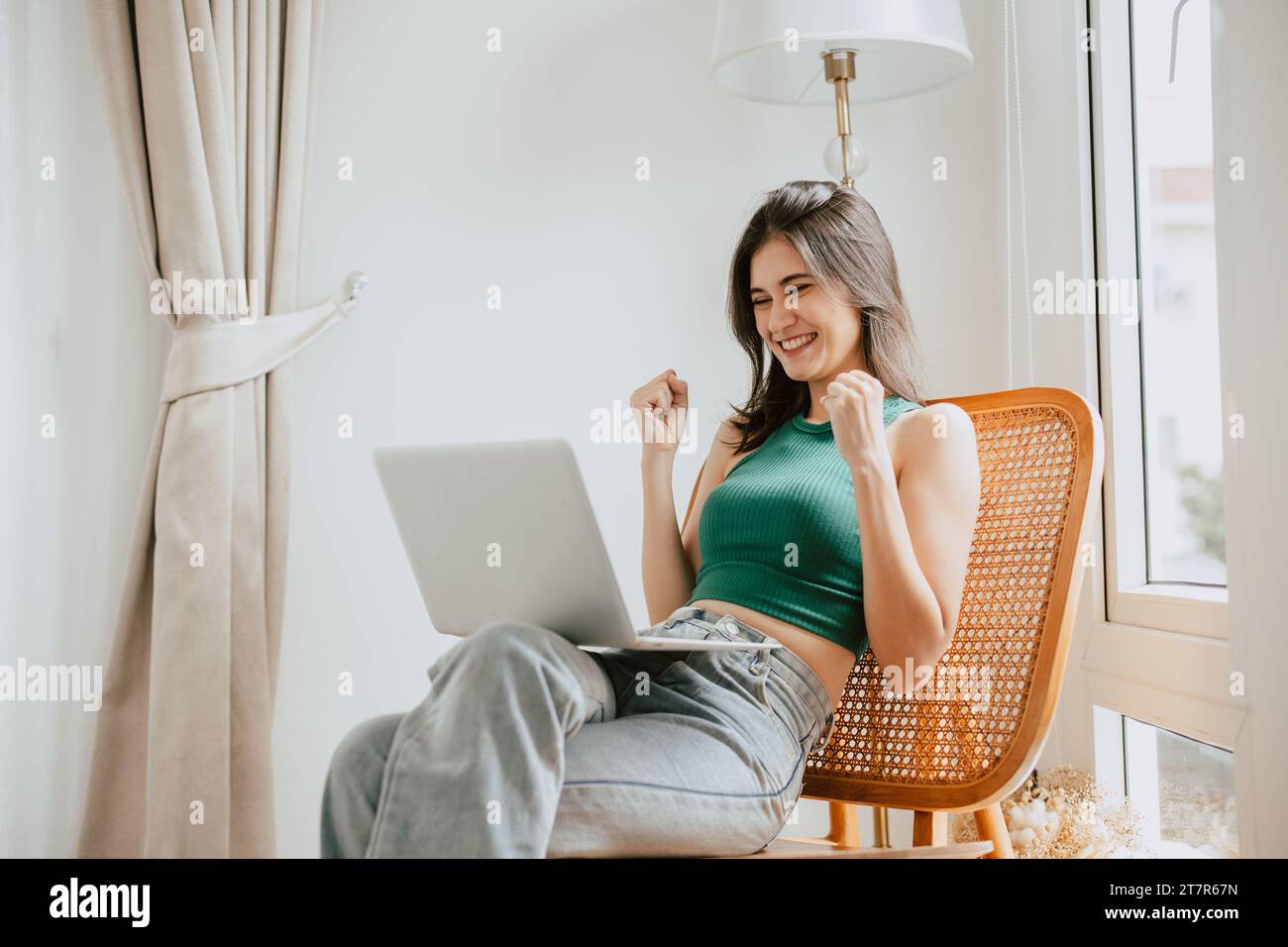 young woman with laptop computer at home happy cheerful success win positive expression Stock Photo