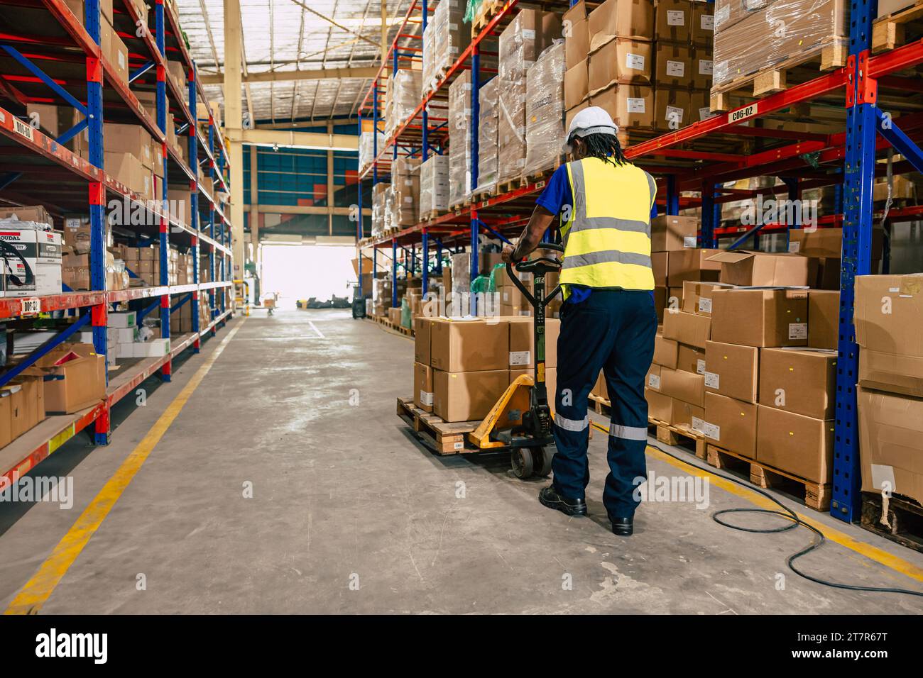 african black warehouse worker using parcel pallet moving cargo for logistics shipping supply management industry Stock Photo