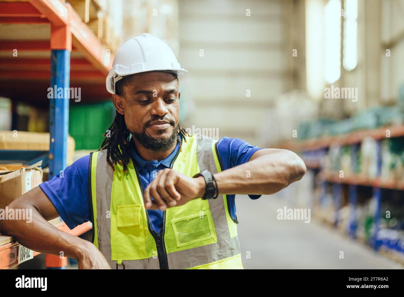African Black people Engineer male worker looking at wristwatch time check. Industry factory working hours afternoon break times for lunch Stock Photo