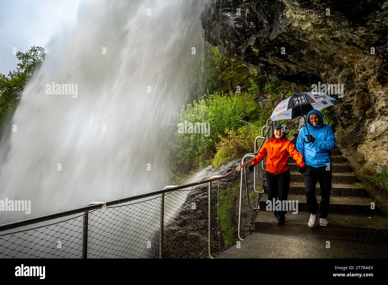 Tourists pass under the Steinsdalsfossen waterfall Stock Photo