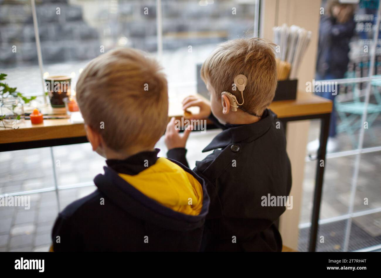 Boy have a Hearing Aids. Two twin brothers in a cafe. Selective focus, shallow depth of field Stock Photo