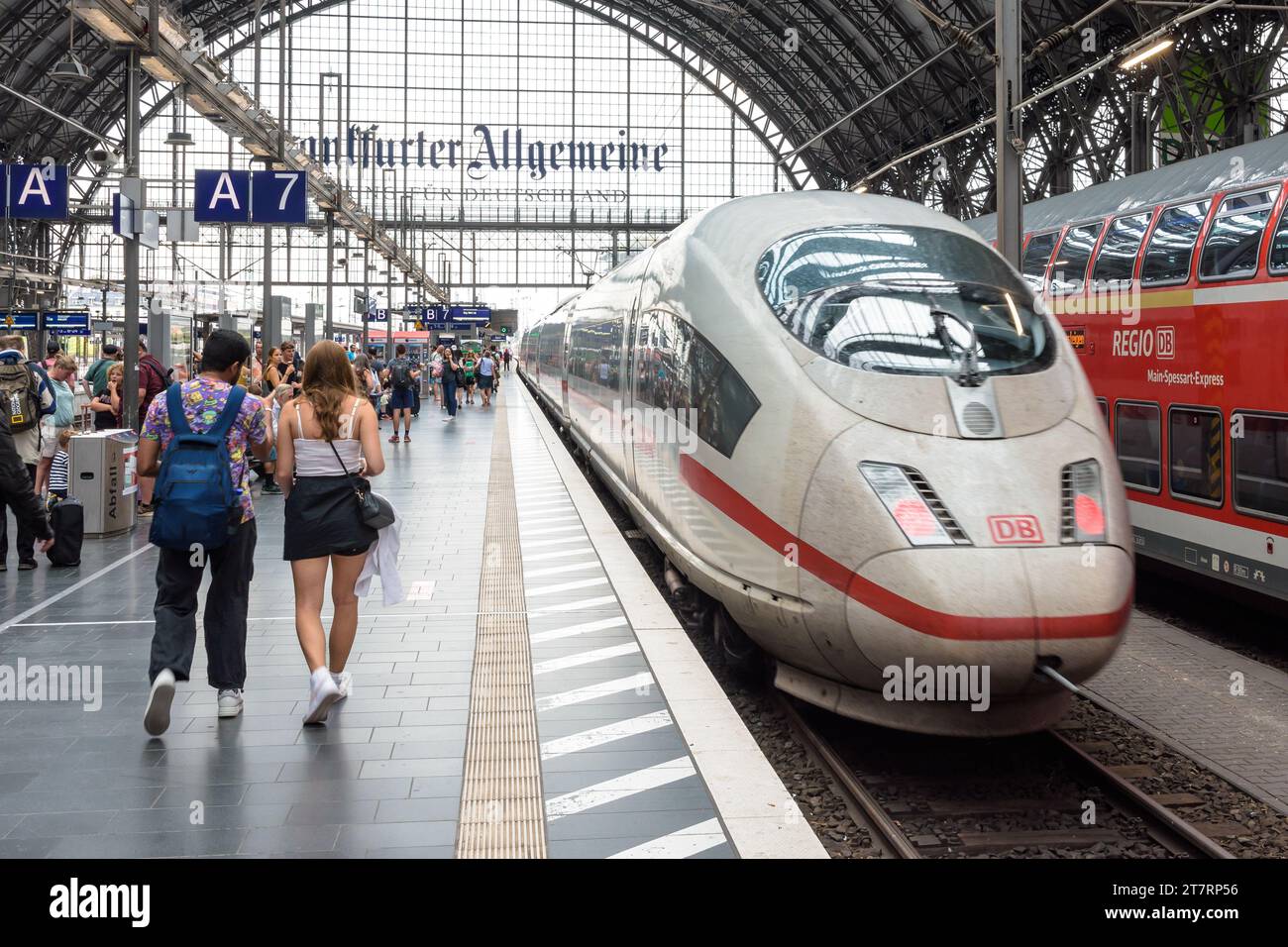 A young couple walk on the platform in Frankfurt Central Station, Germany, as an ICE high speed train leaves. Stock Photo