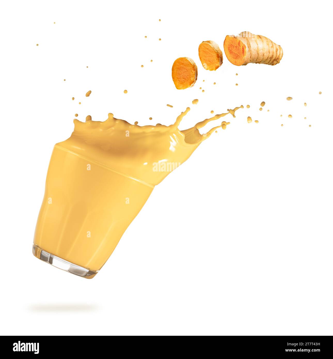 Slices of turmeric flying over a falling glass with overflowing golden milk. Authentic studio shot of antioxidant drink. Stock Photo
