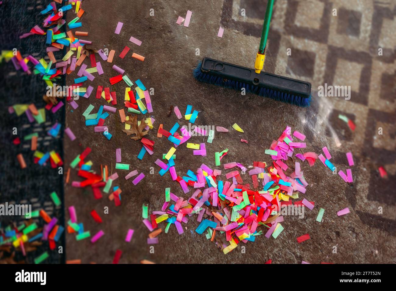 Broom cleaning up confetti from ground outside Stock Photo