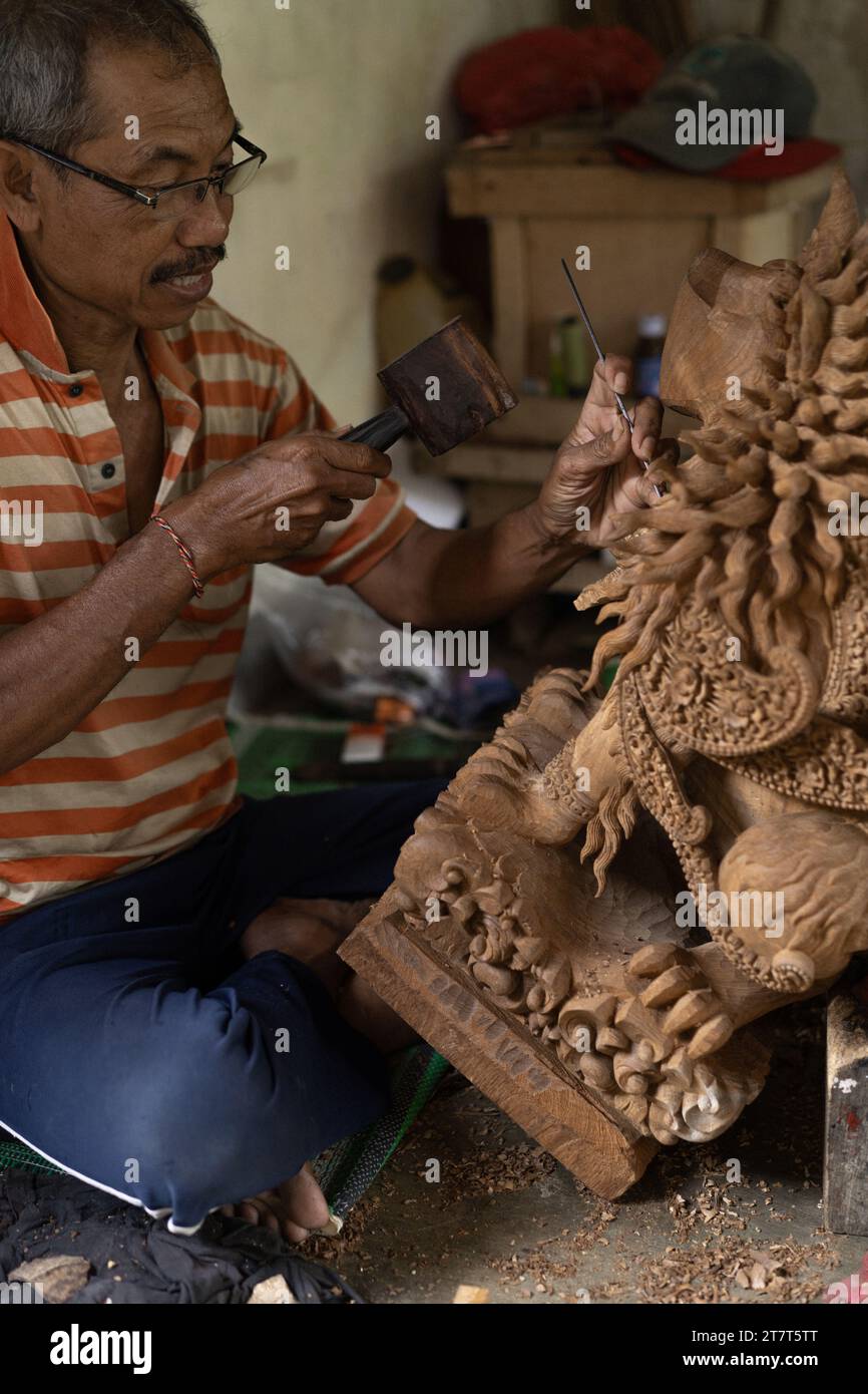 A man carves a statue in wood in workshop. Woodcarving Bali. Stock Photo