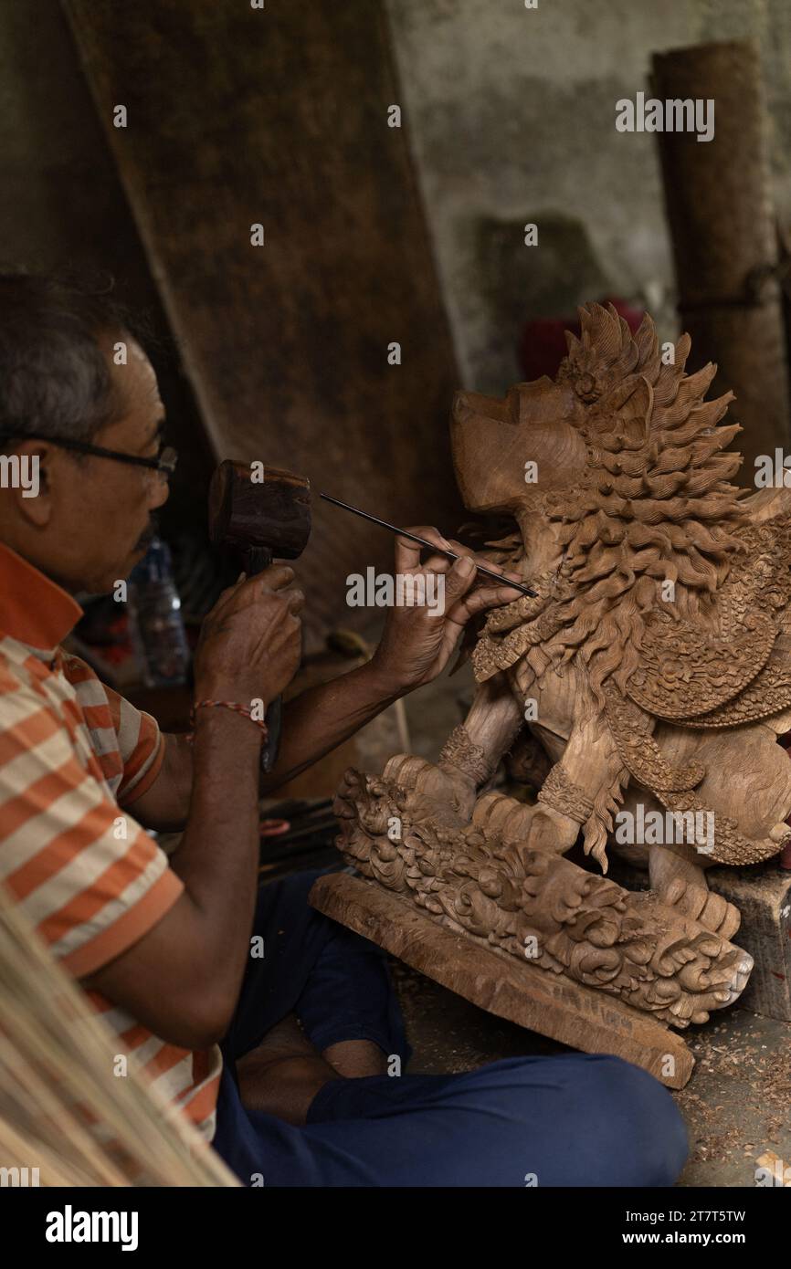 A man carves a statue in wood in workshop. Woodcarving Bali. Stock Photo