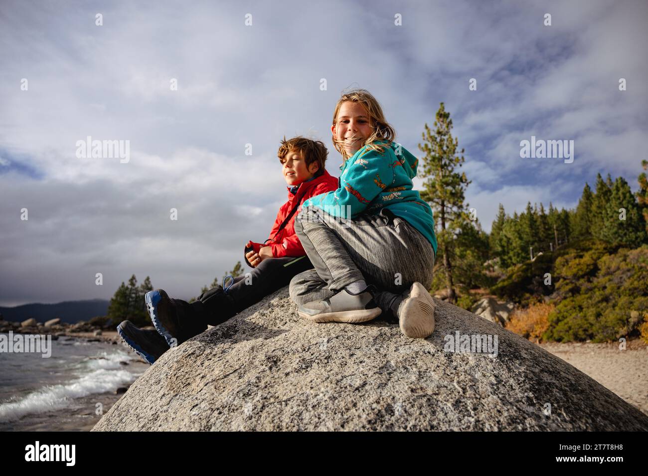 Boy smiling at camera while sitting next to brother on top of boulder Stock Photo