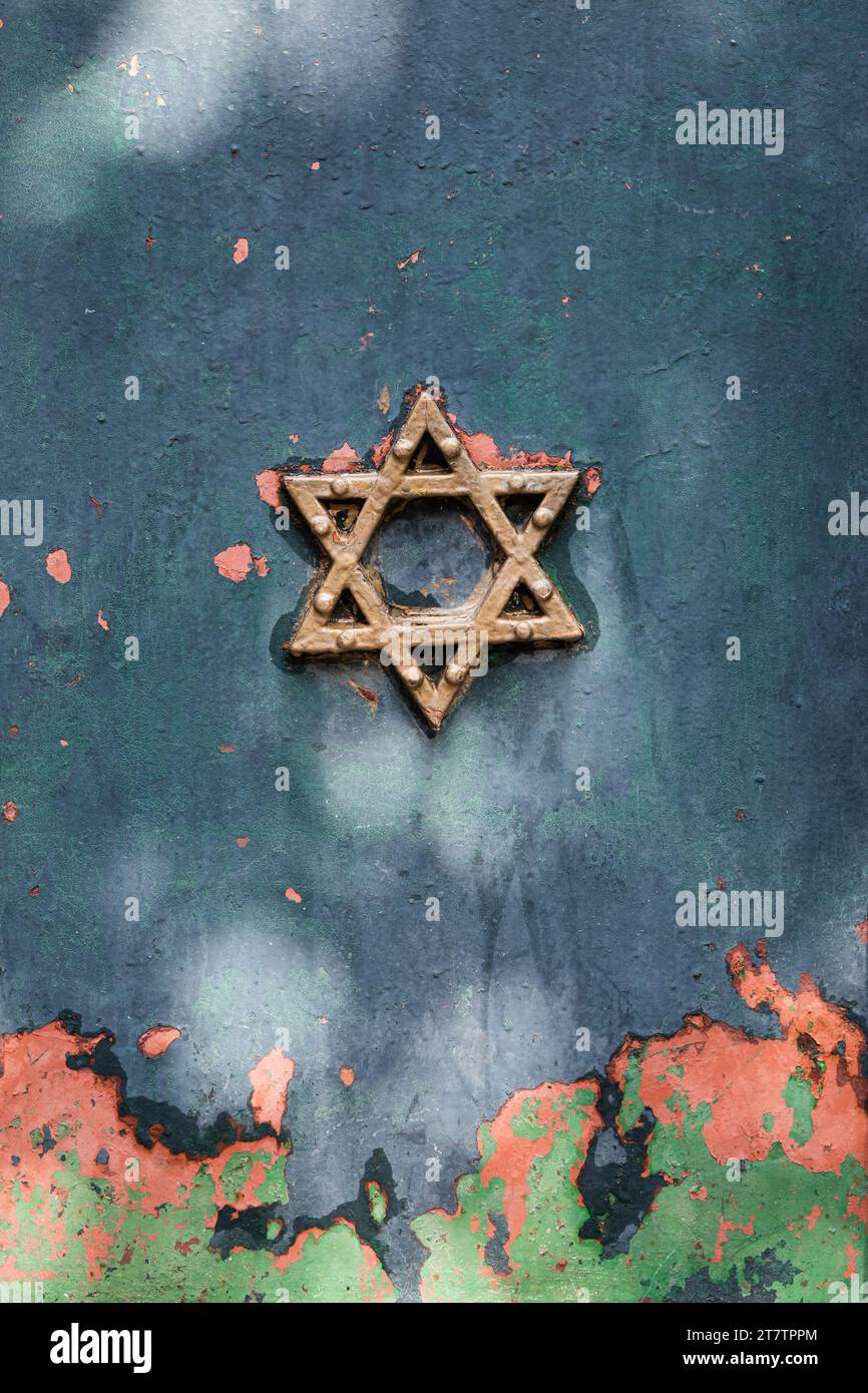 A gold Star of David is embossed on an old metal door with layers of multi-colored, peeling paint. Stock Photo