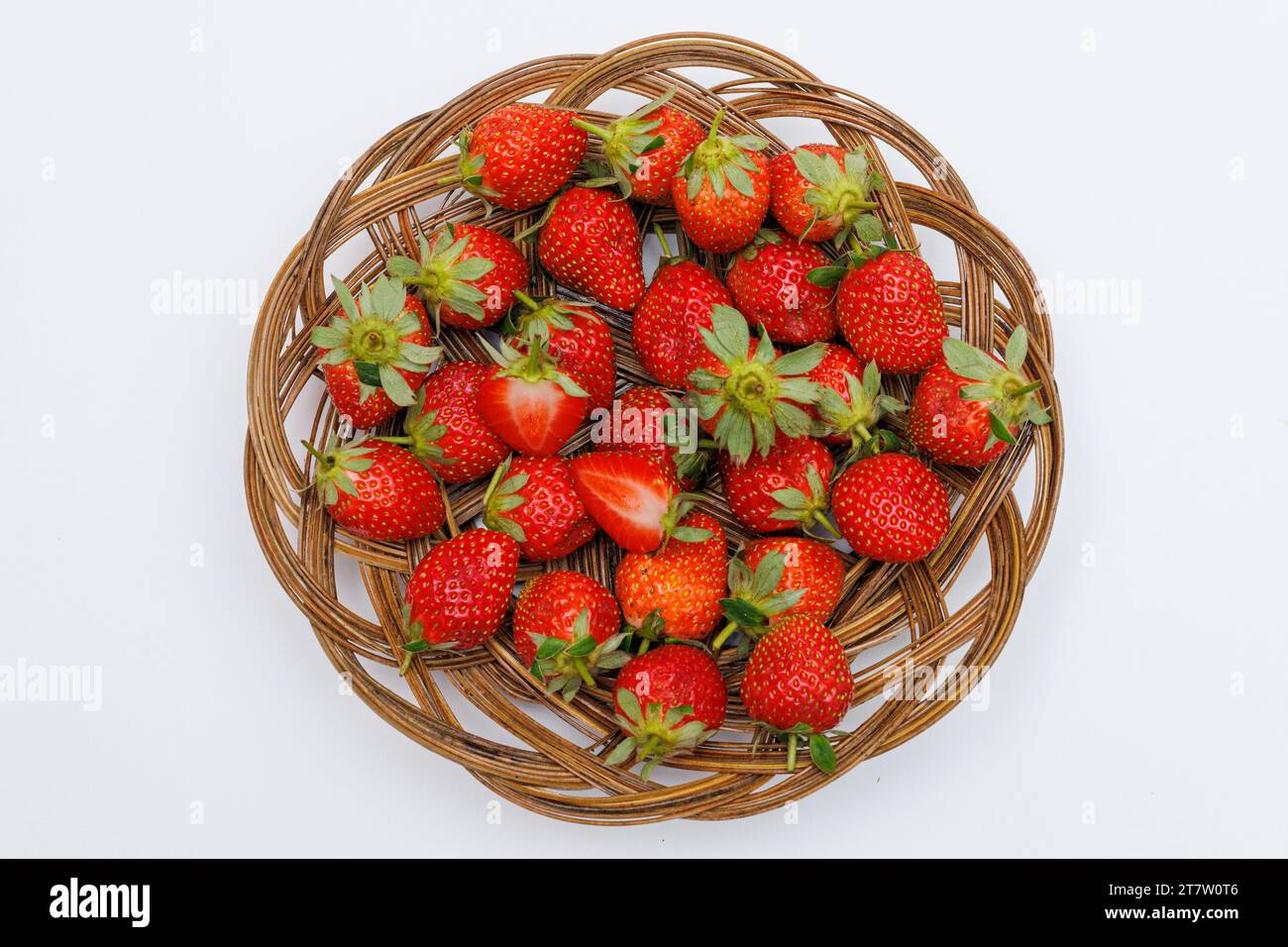 Ripe strawberries in a wicker tray top view on a white background. Stock Photo