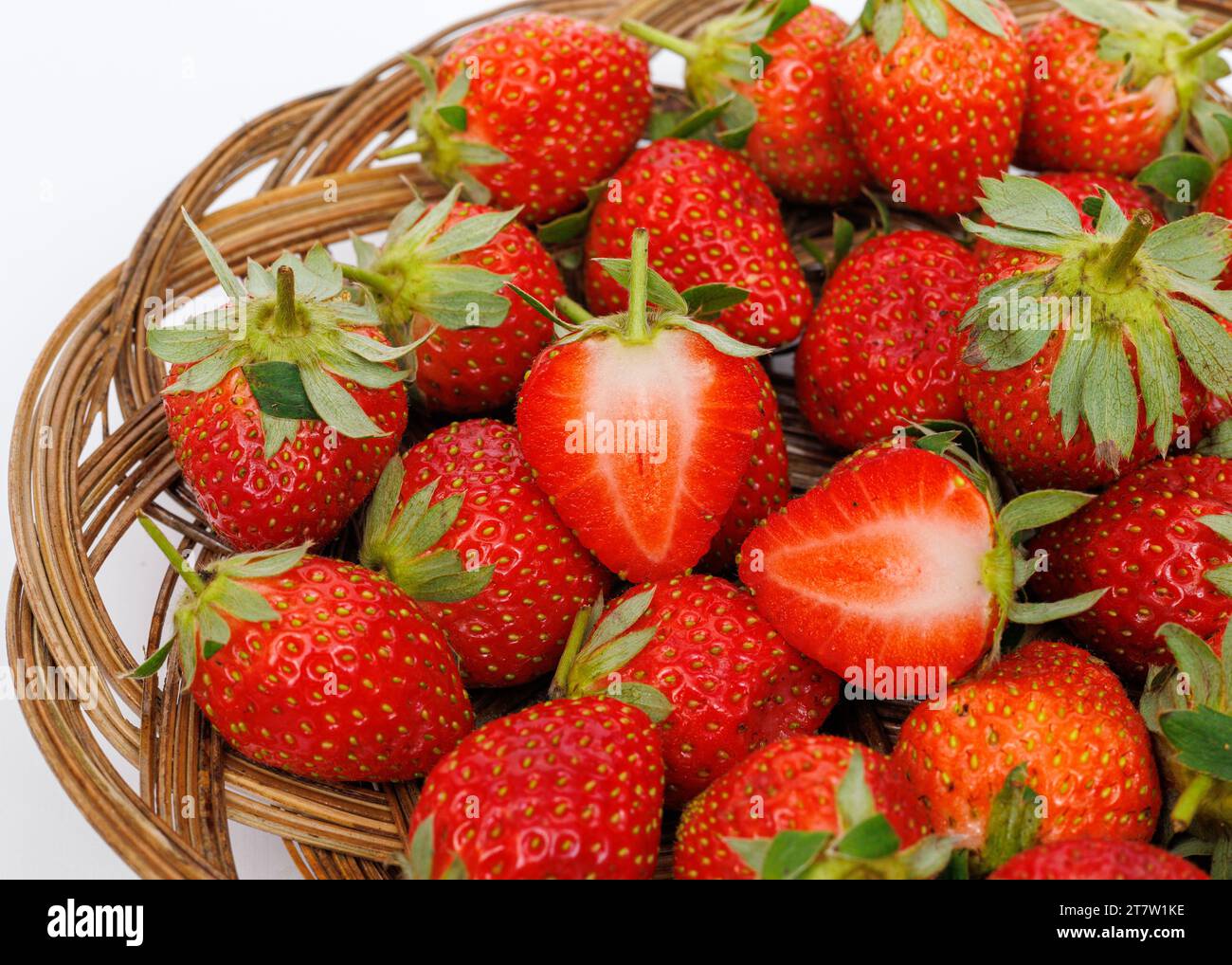 Ripe strawberries in a wicker tray on a white background, close up. Stock Photo