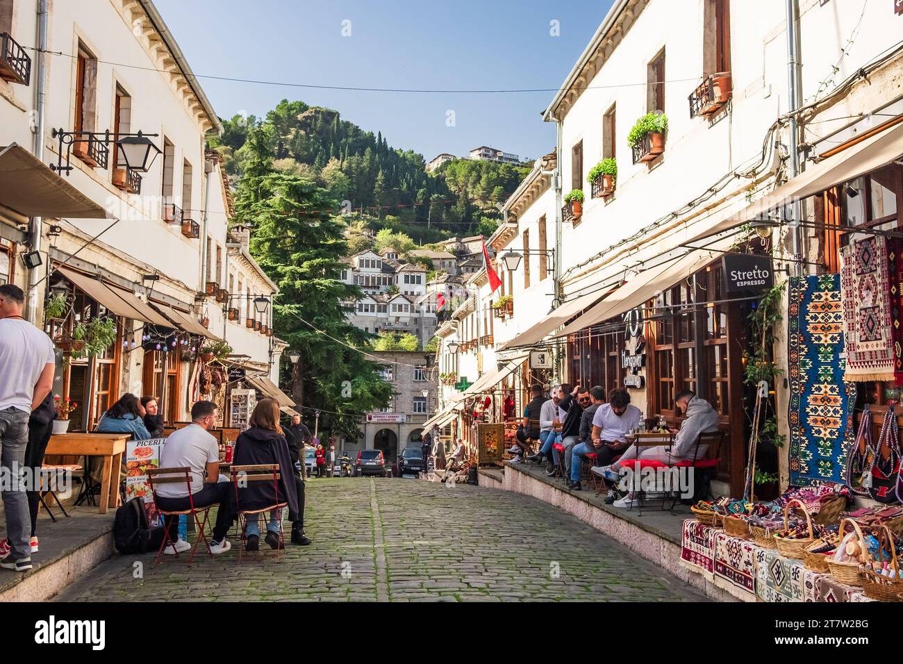 Souvenir shops and restaurants in old town of Gjirokaster in Albania. Old town of Gjirokaster is a World Heritage Site by Unesco. People relaxing and Stock Photo