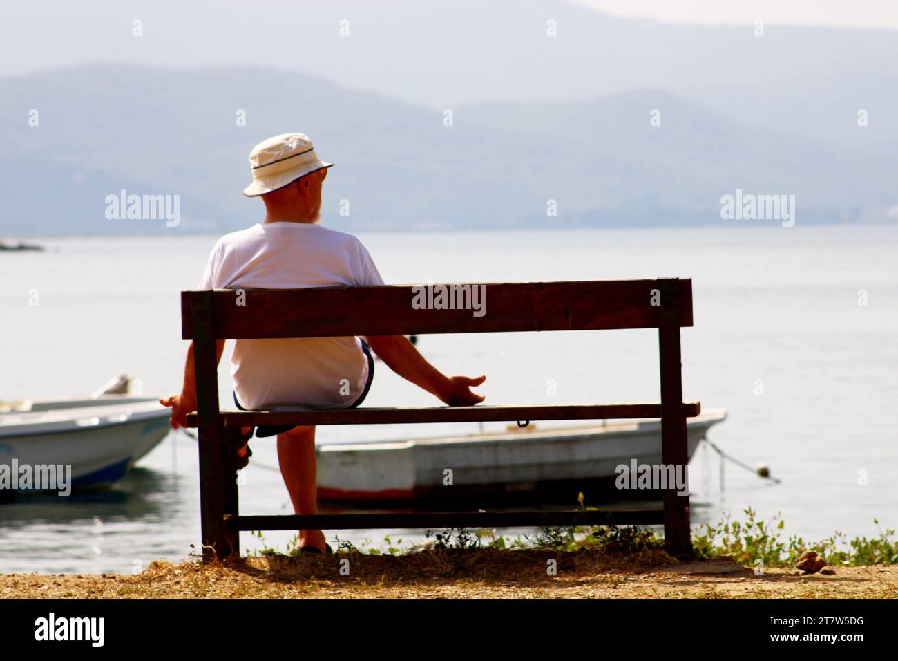 An old lonely man sitting alone on the bench on the beach Stock Photo ...