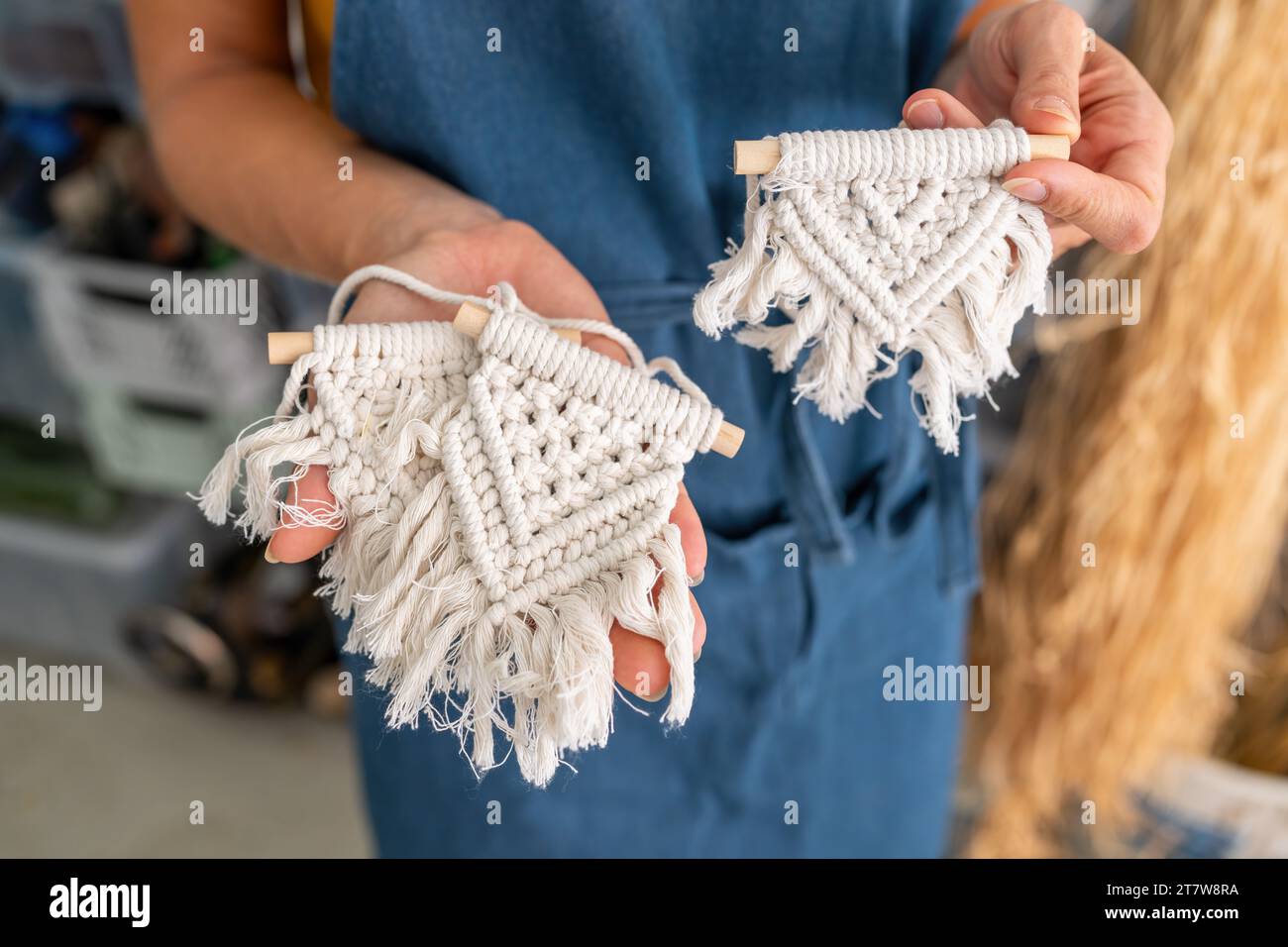 Close-up of a person holding two small macrame wall hangings Stock Photo