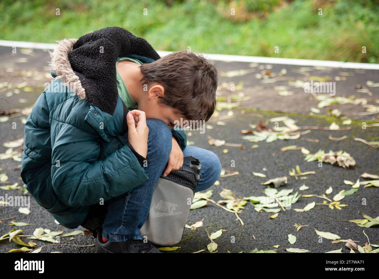 A young boy in early teens, navigating the challenges of autism,  distressing moment on the pavement, expressing his emotions in a melt-down Stock Photo