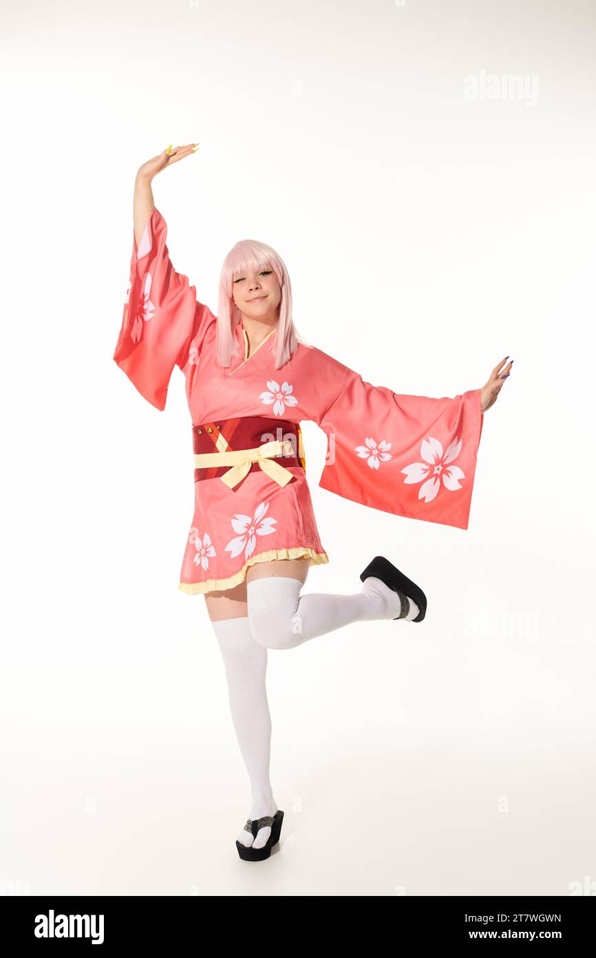 cheerful anime style woman in vibrant traditional attire posing on white, japanese cosplay culture Stock Photo