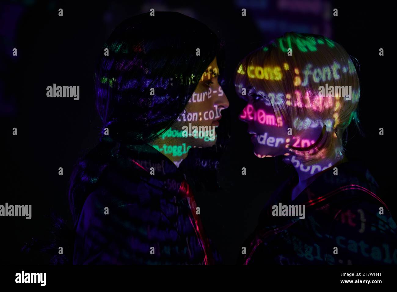 side view of young couple with neon programming lettering on dark ...