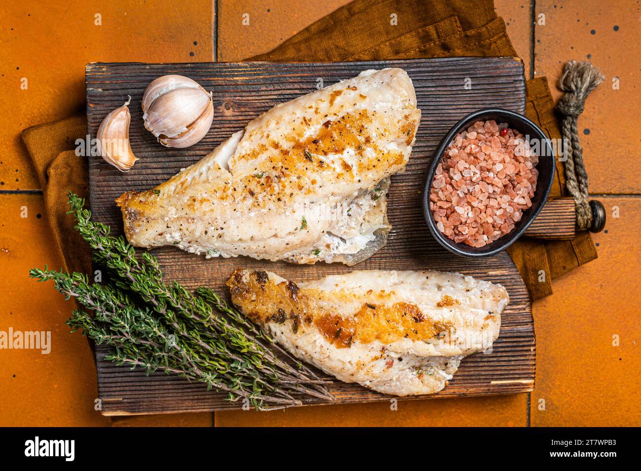 Roast sea red perch fillet, redfish fish on wooden board. Orange background. Top view. Stock Photo