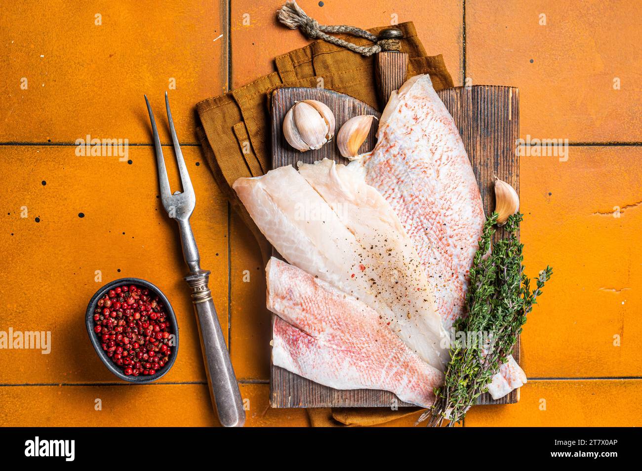 Uncooked ocean red perch fillet, redfish with herbs and spices. Orange background. Top view. Stock Photo
