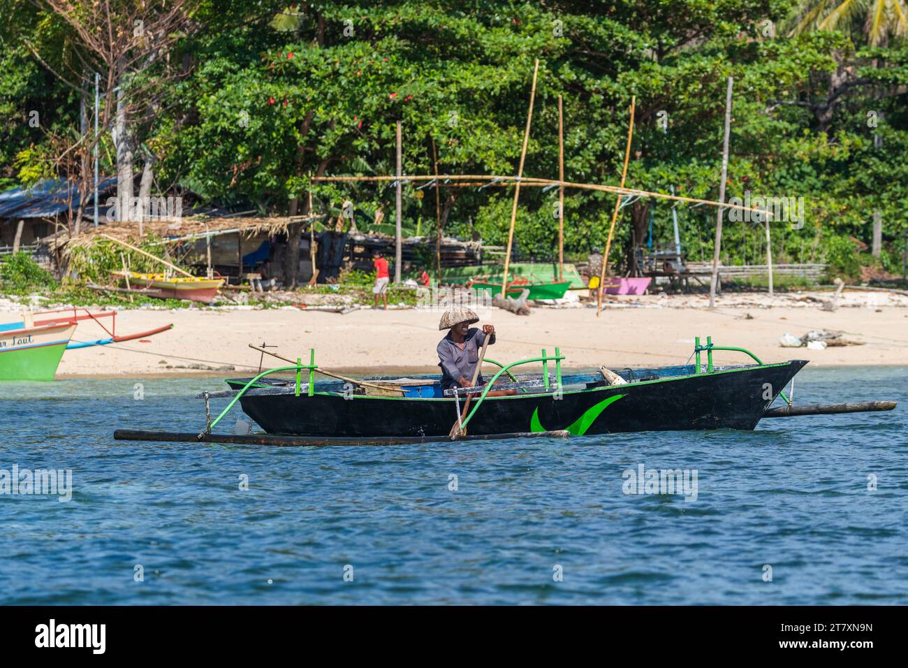 Local fisherman in outrigger boat in the shallow reefs off Bangka Island, off the northeastern tip of Sulawesi, Indonesia, Southeast Asia, Asia Stock Photo