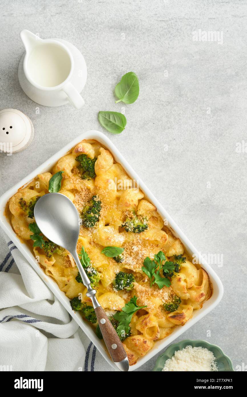 Pasta Broccoli casserole. Baked Mac and cheese with broccoli, cream sauce and parmesan on gray light concrete table background. Healthy or baby food. Stock Photo