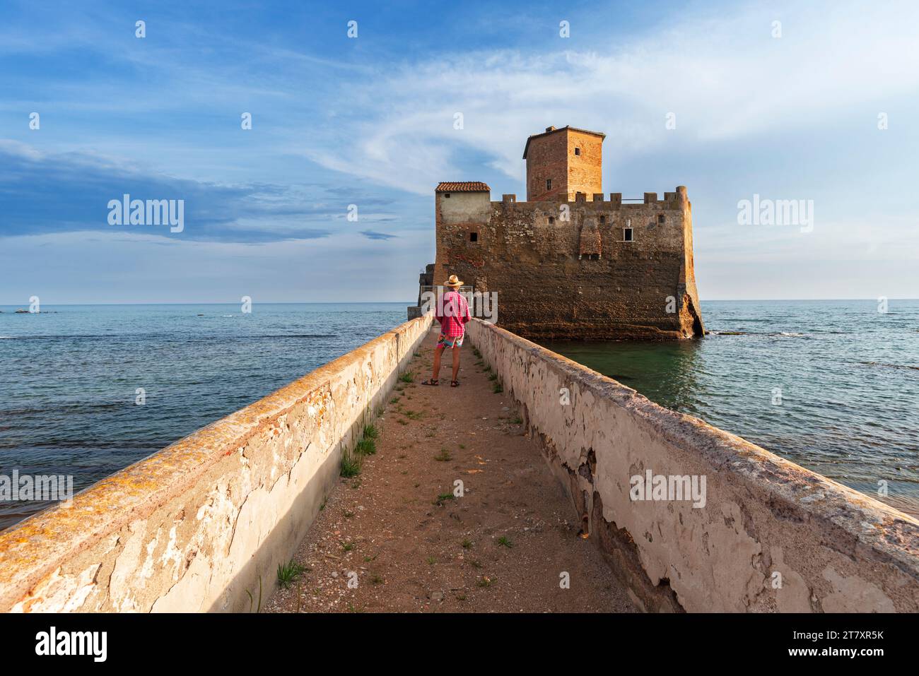 Tourist standing on top of the boardwalk admiring Torre Astura Castle, Nettuno municipality, province of Rome, Tyrrhenian sea, Latium (Lazio), Italy, Stock Photo