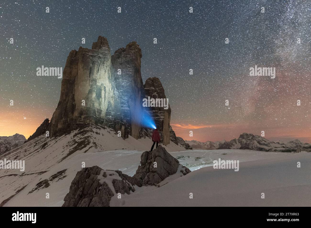 Hiker with head torch views the Tre Cime di Lavaredo on a starry night with the Milky Way, winter view, Tre Cime di Lavaredo (Lavaredo peaks) Stock Photo