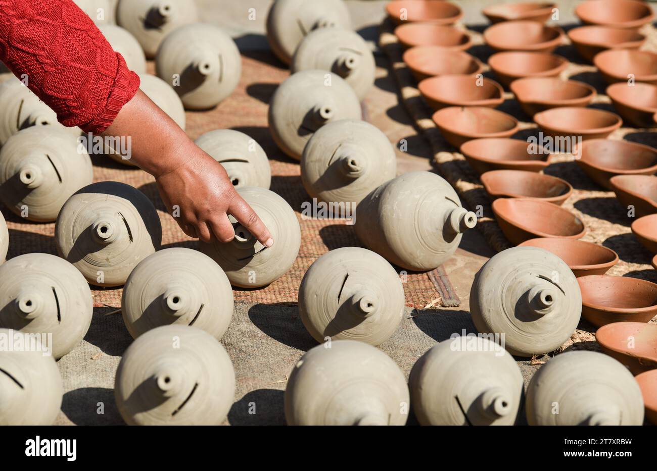 A craftswoman shows off the traditional clay pots she left to dry in the sun, Bhaktapur, Nepal, Asia Stock Photo