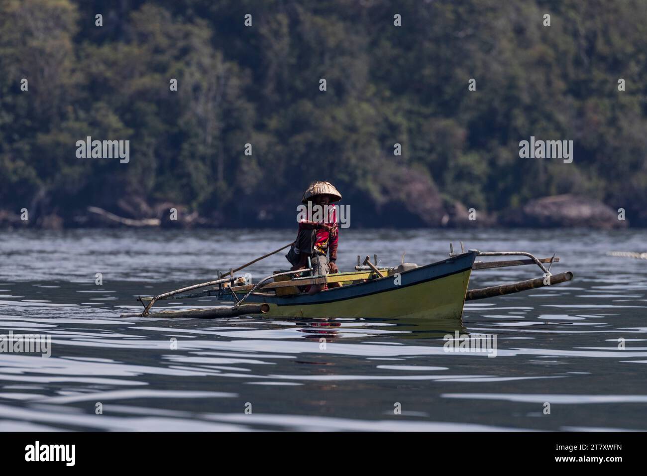 Fisherman in an outrigger canoe, Bangka Island, off the northeastern tip of Sulawesi, Indonesia, Southeast Asia, Asia Stock Photo
