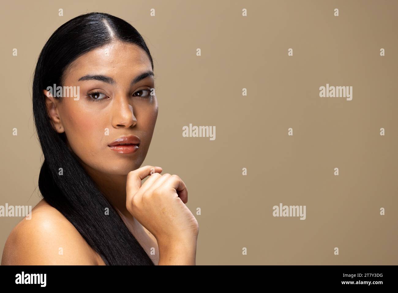 Portrait of biracial woman with dark hair and natural make up on brown background, copy space Stock Photo