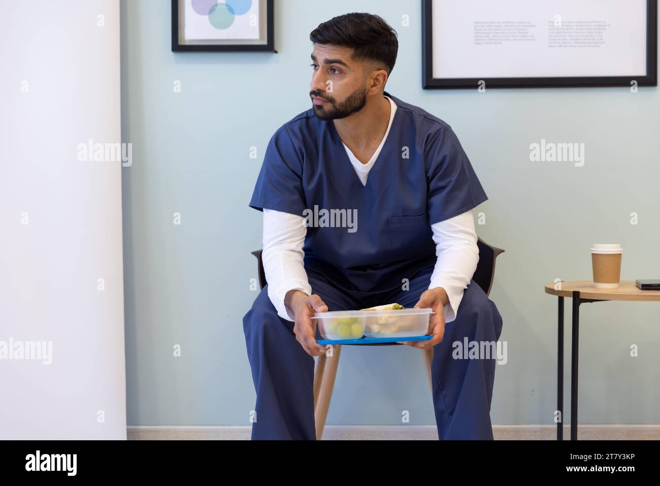 Biracial male doctor having lunch in hospital waiting room Stock Photo
