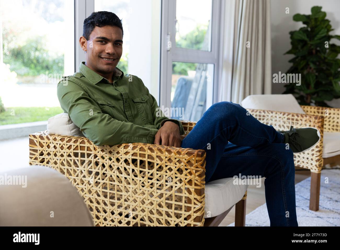 Portrait of happy biracial man sitting on armchair at home Stock Photo