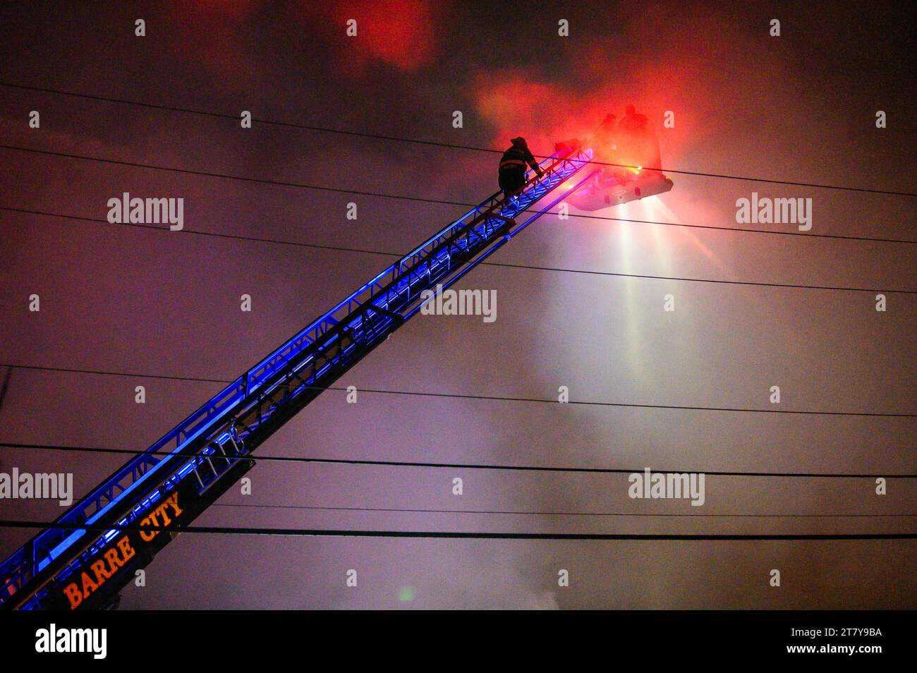 Fire fighters firemen on long ladders in action to fight a spectacular blase at the RK Miles lumberyard in Montpelier, VT, New England, USA. Stock Photo