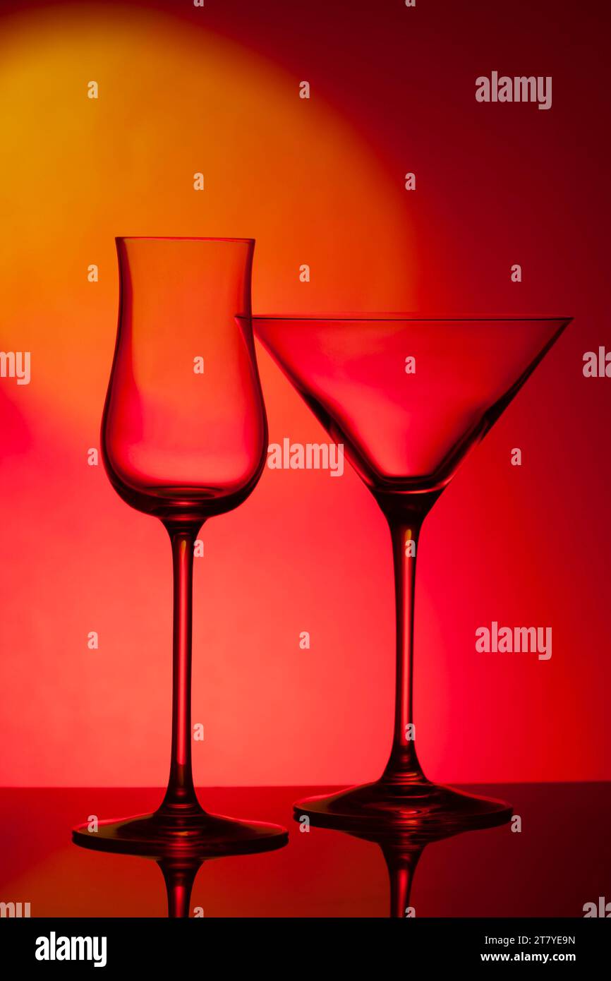 Empty glass wine glass on a red background. Wine glass for a drink on a red background. Dark silhouette of a glass. Stock Photo