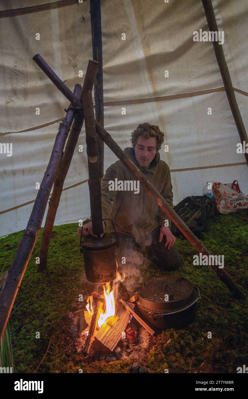 young man cooking in tipi tent Stock Photo