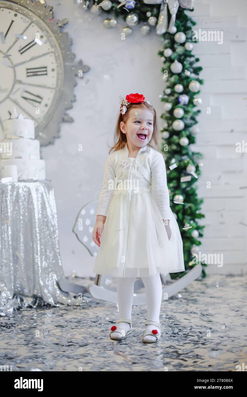Cute little girl in a white dress with a red bandana on her head stands ...