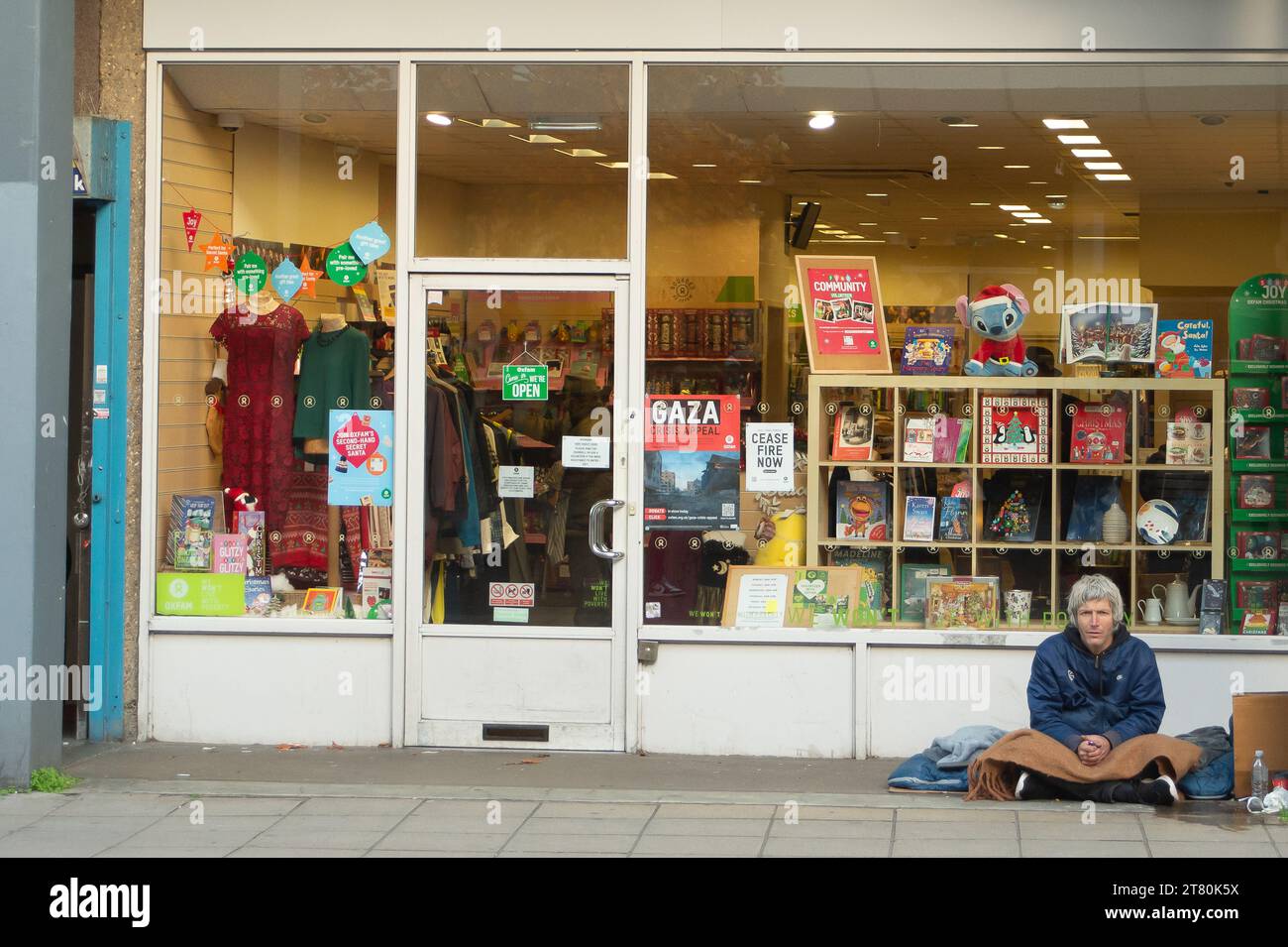 Uxbridge, UK. 17th November, 2023. A homeless man sits outside an Oxfam