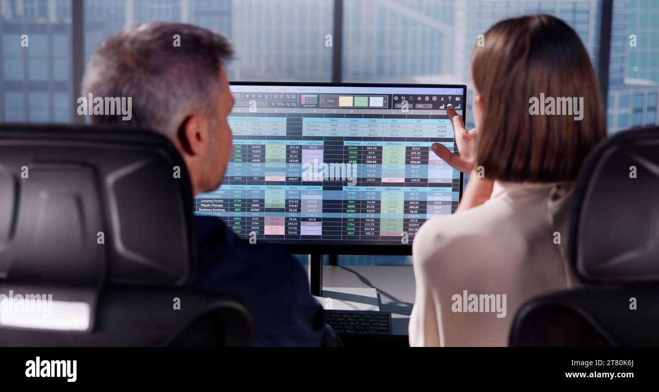 Working Analyst at Desktop Computer with Spreadsheets Stock Photo