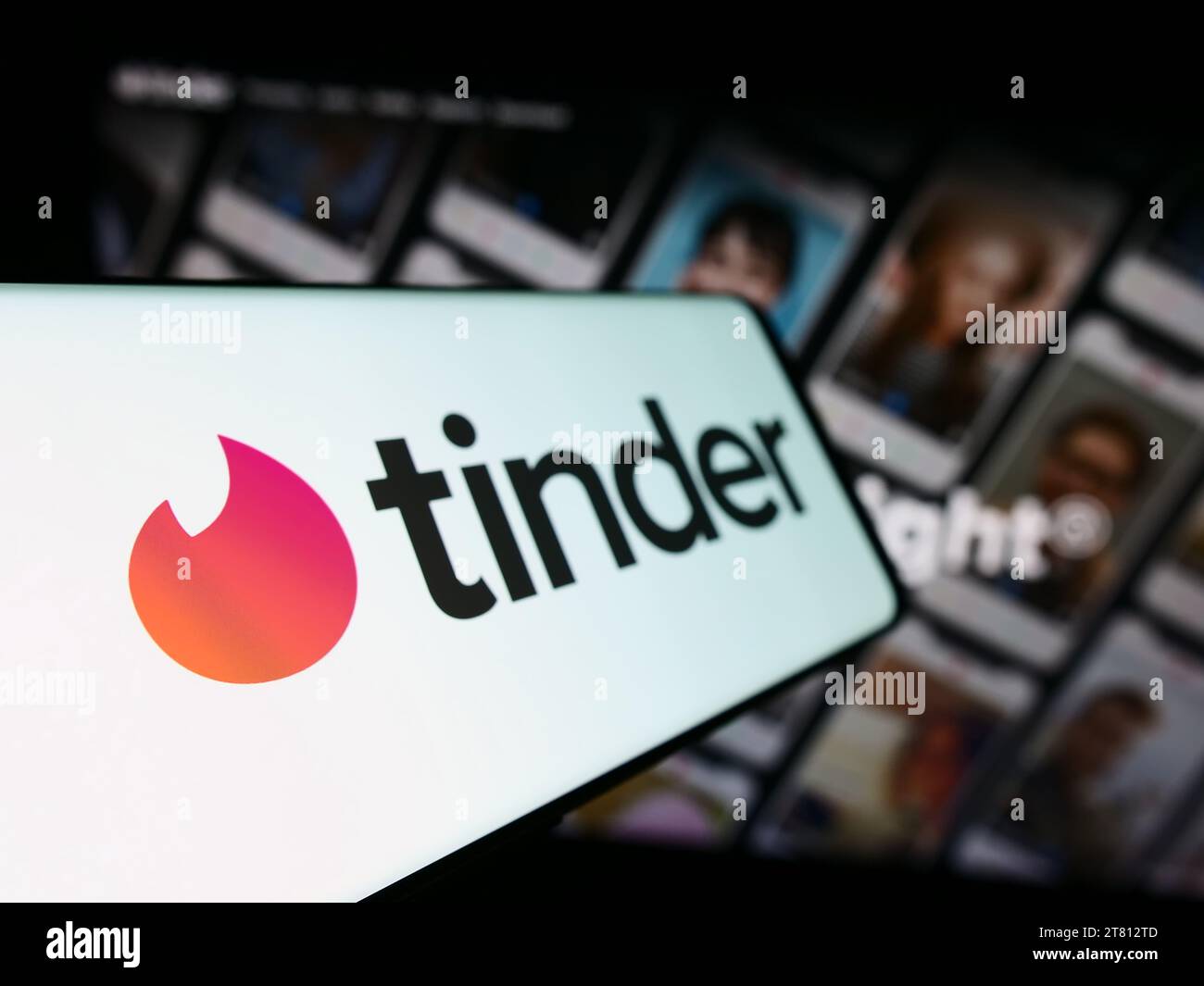 Mobile phone with logo of American online dating app Tinder in front of business website. Focus on left of phone display. Stock Photo