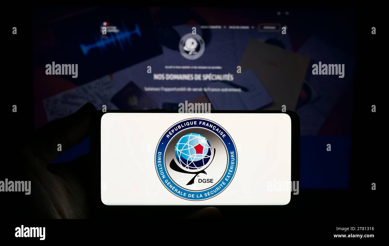 Person holding smartphone with logo of Direction Generale de la Securite Exterieure (DGSE) in front of website. Focus on phone display. Stock Photo