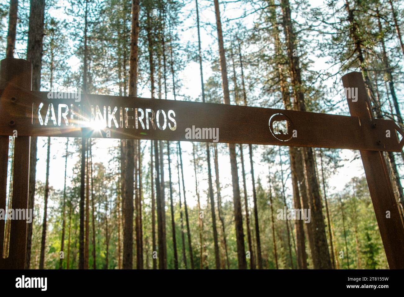 The sun shines through a sign post on the bear hiking trail in northern Finland Stock Photo