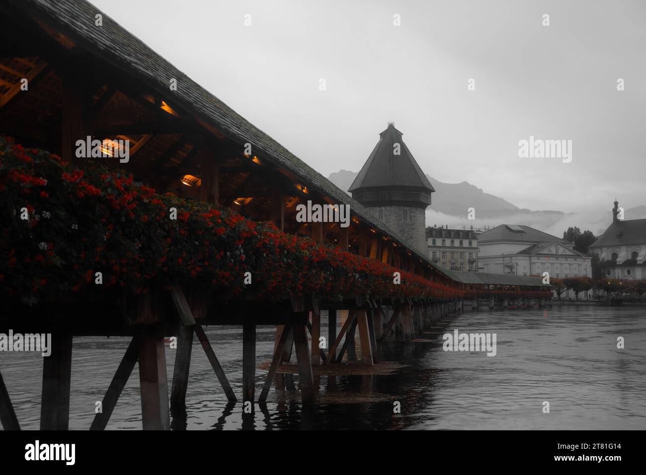 A wooden bridge stands against a backdrop of stunning mountain scenery, with vibrant floral foliage above it Stock Photo