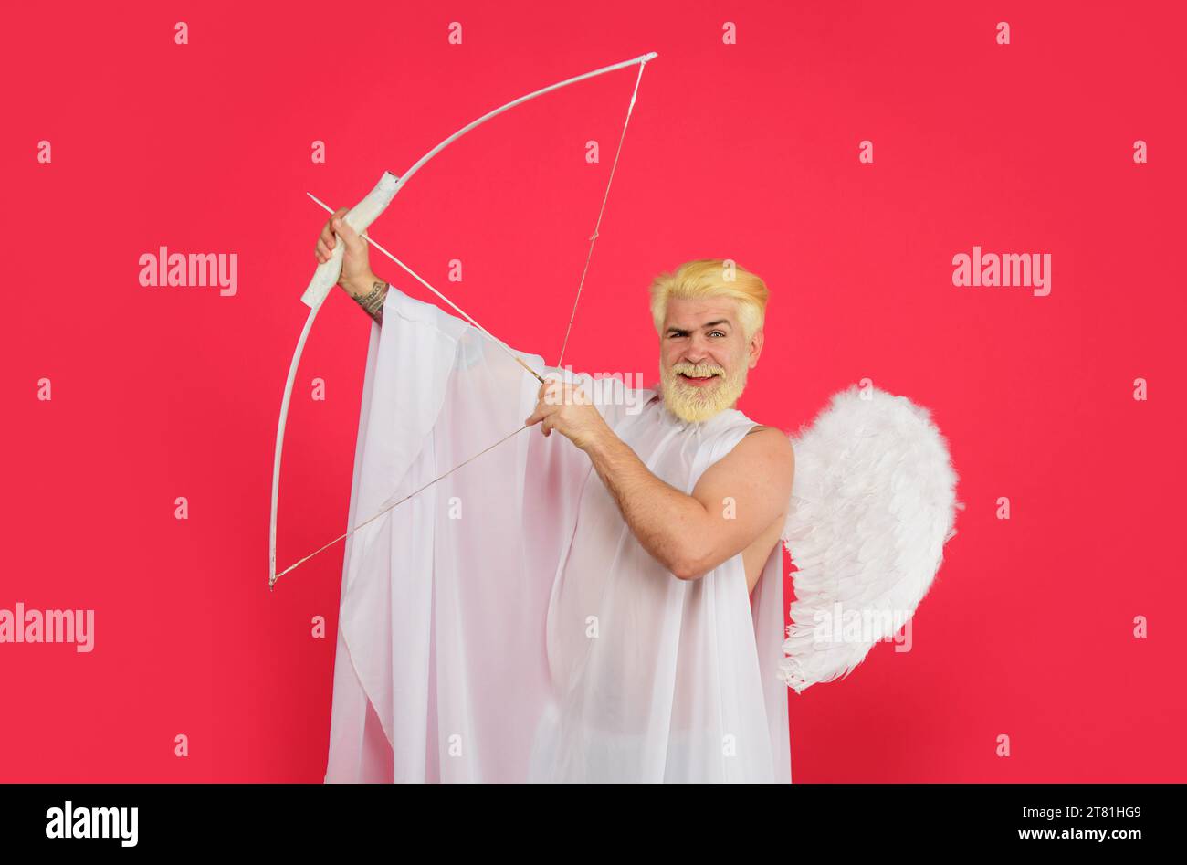 Happy Valentines Day. Cupid angel with bow and arrows. Smiling bearded man in white angel wings shooting love arrow. Male angel with bow and arrow in Stock Photo