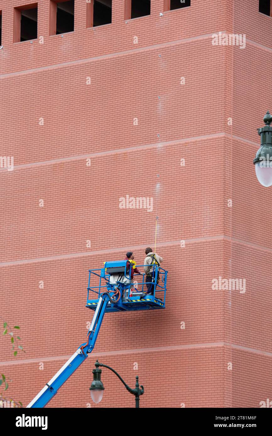 Detroit, Michigan - Workers measure and mark the side of the Bricktown Parking Garage in preparation for hanging a display. Stock Photo