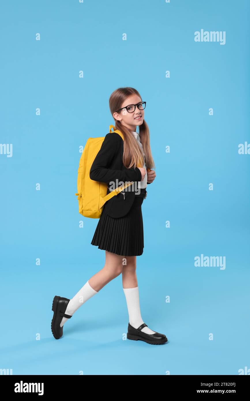 Happy schoolgirl with backpack on light blue background Stock Photo - Alamy