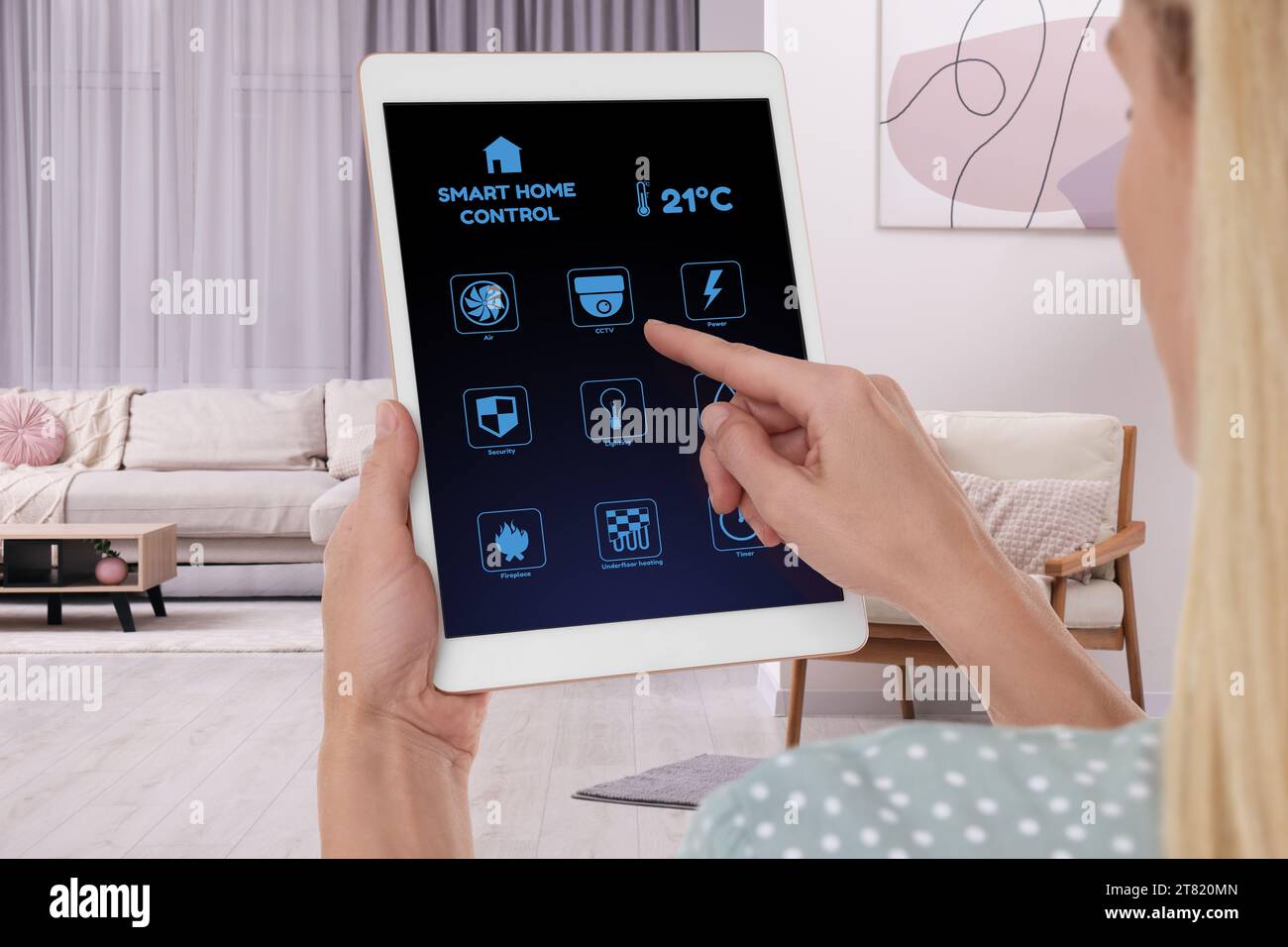 Woman using smart home control system via application on tablet indoors, closeup Stock Photo