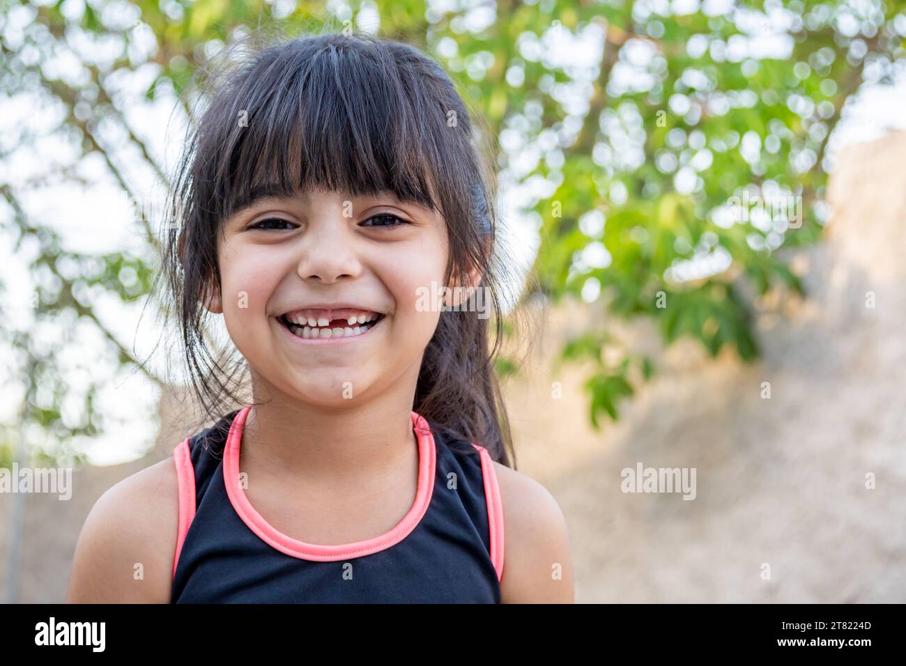 Close-up portrait of her. She is friendly, charming, sweet, curious and cheerful. Little girl outdoors in sports clothing. Stock Photo